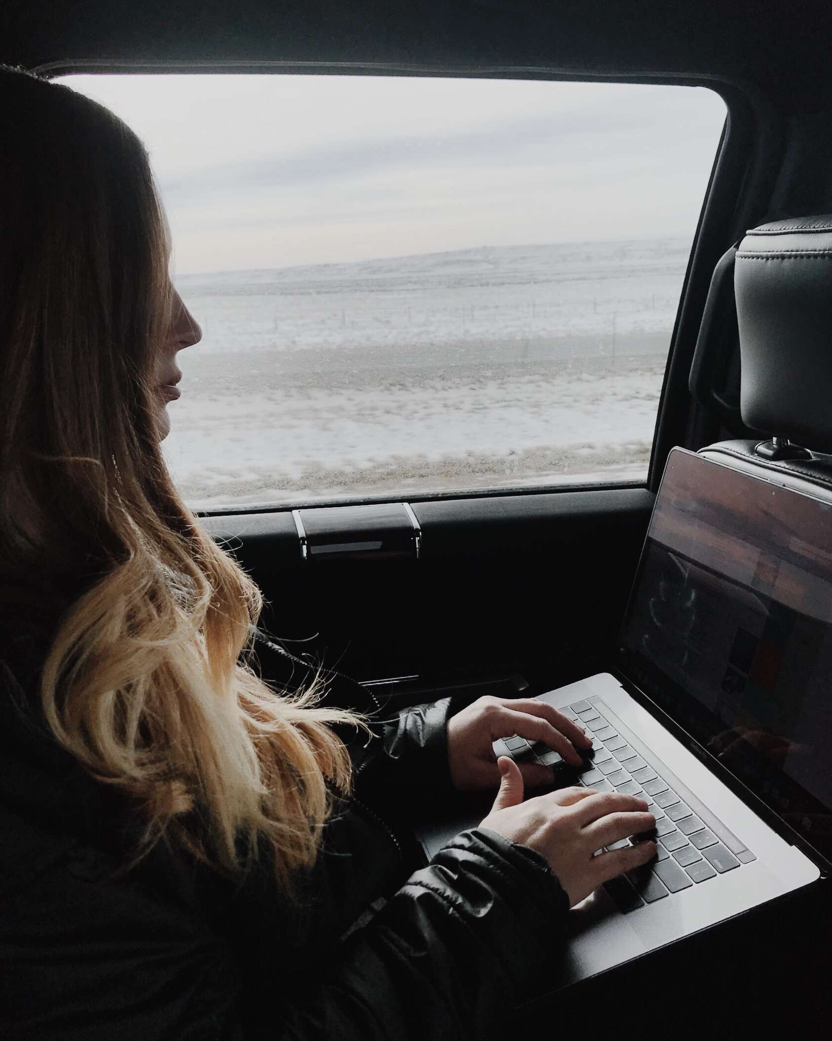 How I Became a Web Designer (And Built a Career I Love) | Westco Web Design Woman typing on a laptop by a large window with natural light streaming in.