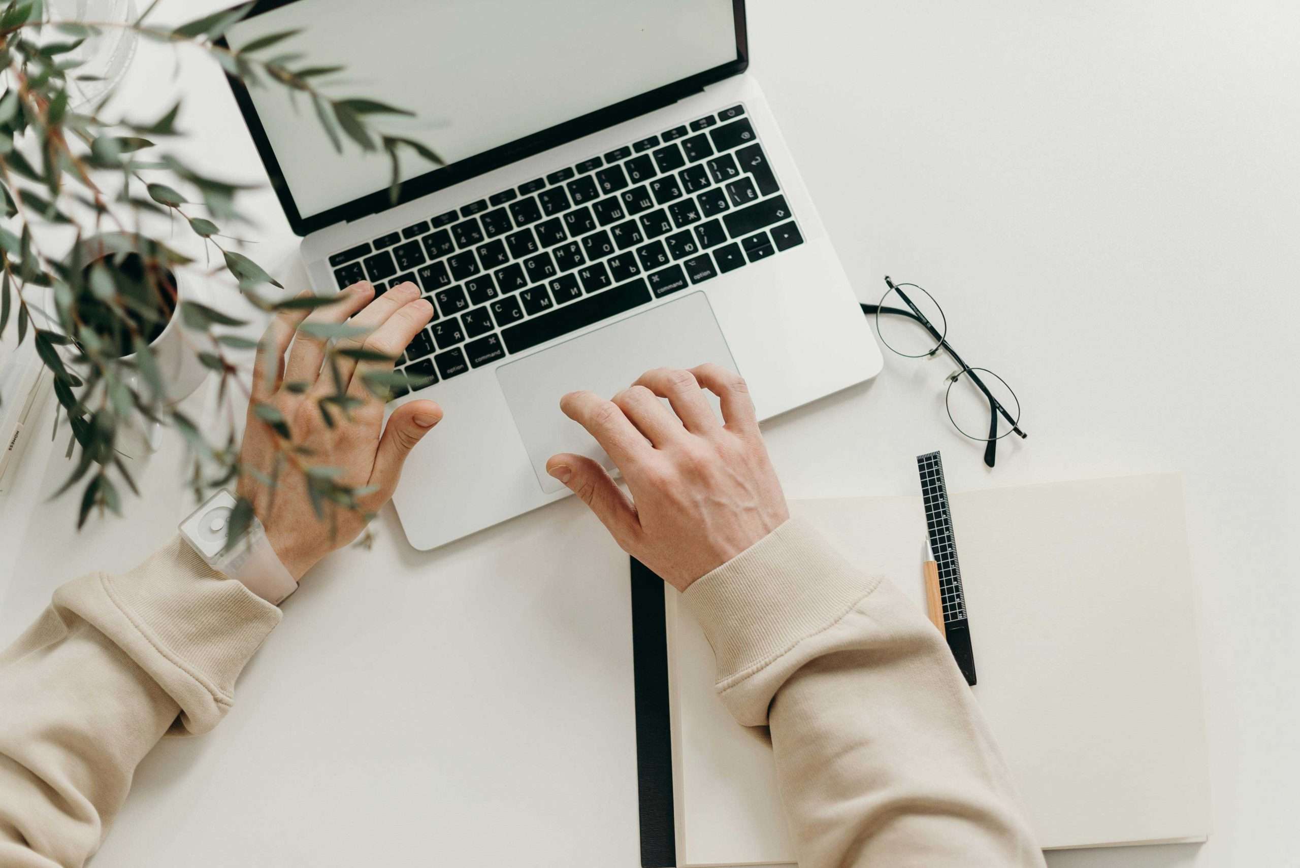 SEO Simplified: Top 15 SEO Terms to Know in 2025 | Westco Web Design Person typing on a laptop at a minimalist desk with a notebook and glasses.