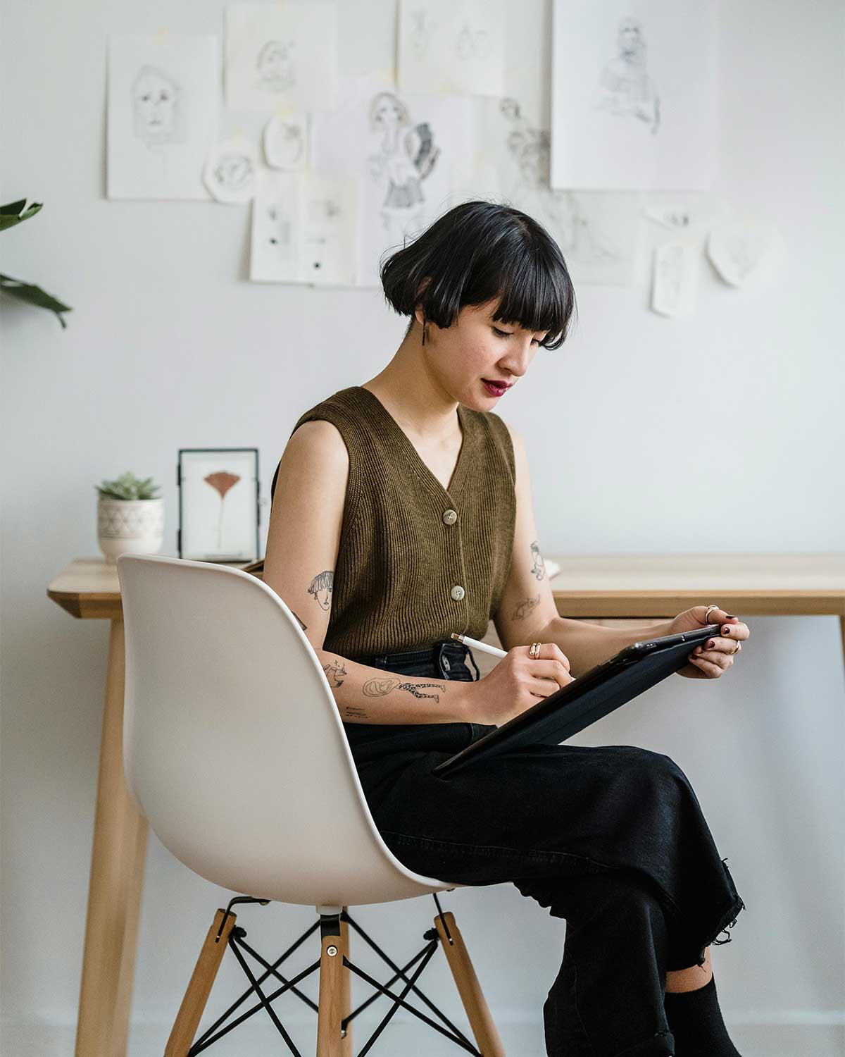 Designer working on a tablet in a modern home studio, highlighting the personalized approach of hiring a web designer compared to AI website builders.