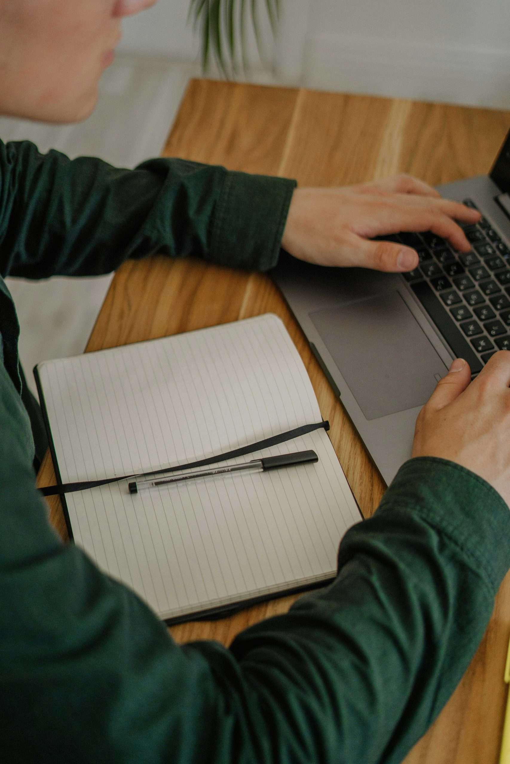 Person working on laptop with open notebook while running a DIY SEO audit.