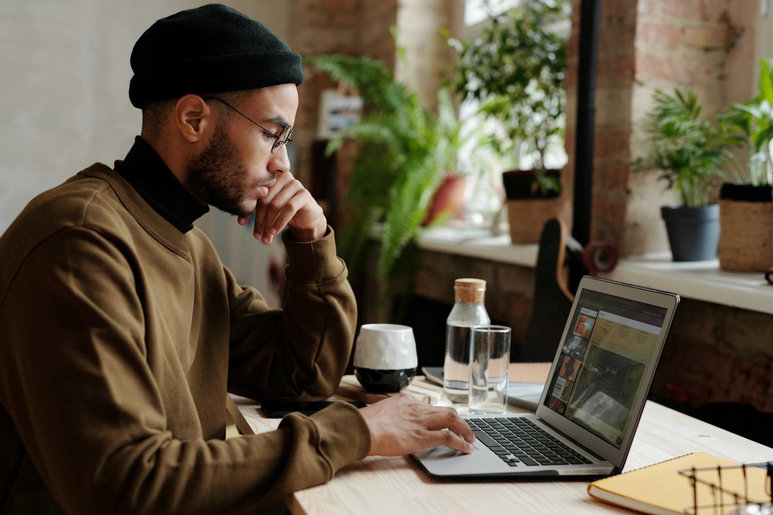 Man building a website on a laptop in a cozy workspace, illustrating the DIY experience of using an AI website builder.