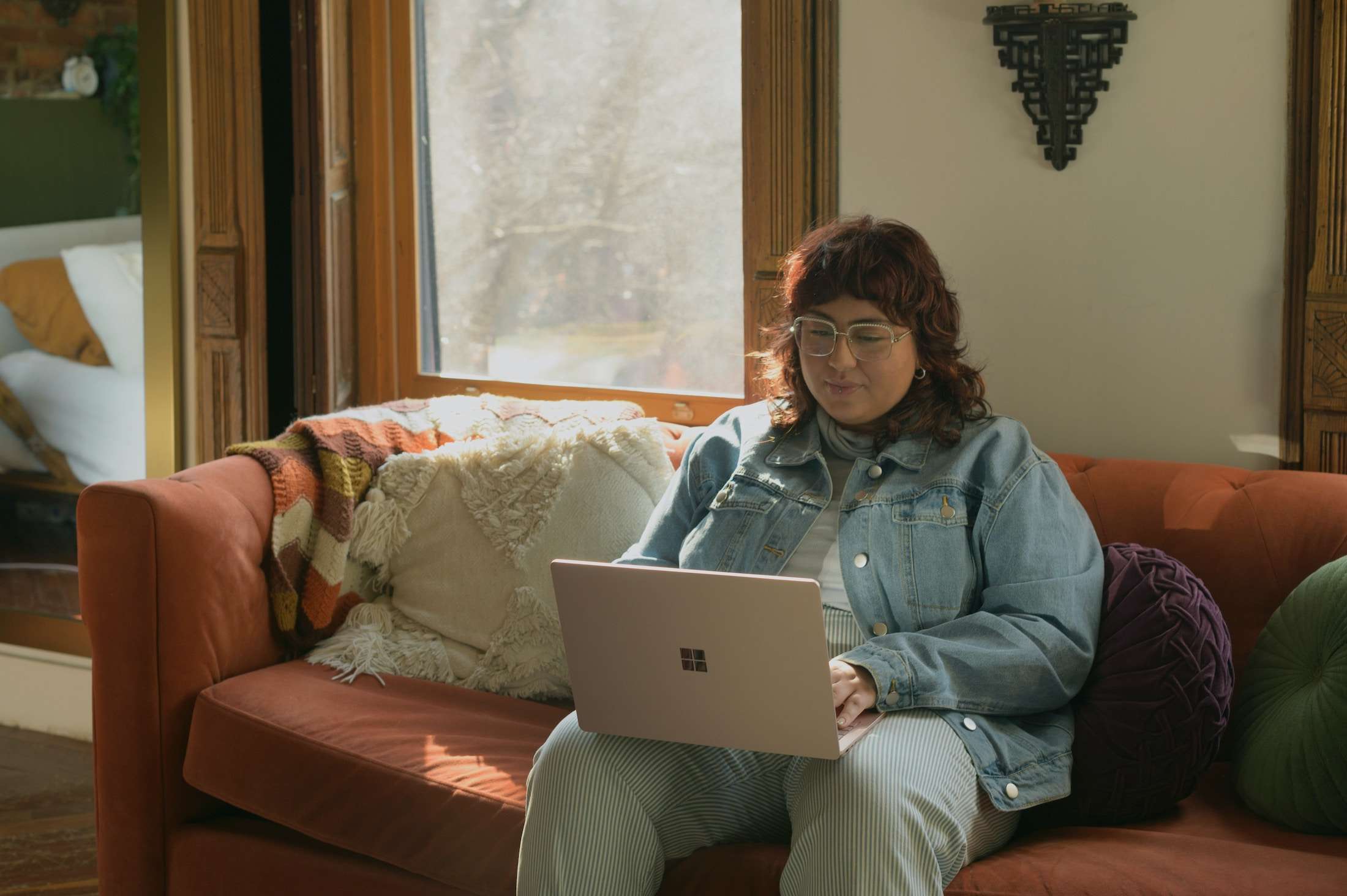 4 SEO Strategies That Still Matter in 2025 (Even In The Age of AI) | Westco Web Design Entrepreneur sitting on a burnt orange couch with notebook and laptop, planning website SEO strategy.