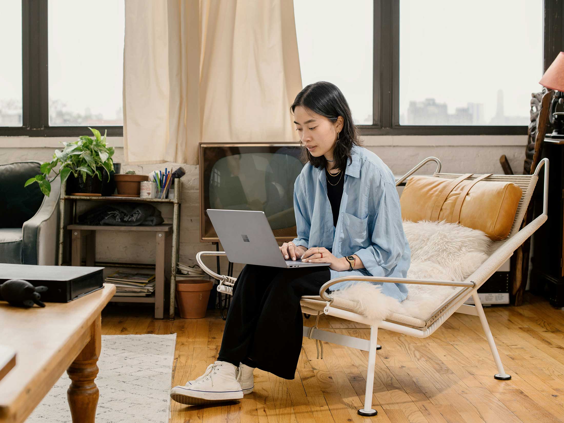 Woman sitting on tan leather chair working on laptop — book a website strategy session for expert guidance.